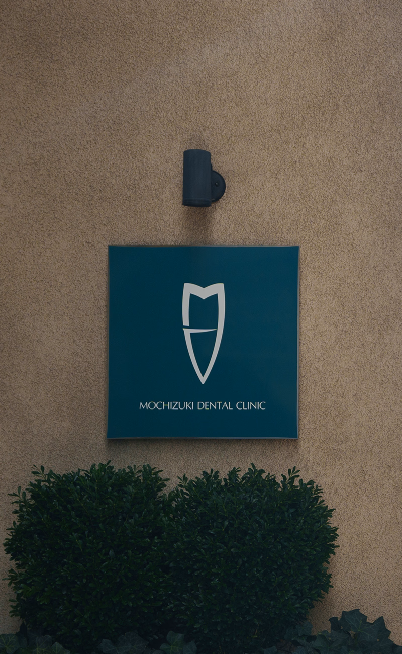 MOCHIZUKI DENTAL CLINIC のロゴ看板が外壁に設置されている様子