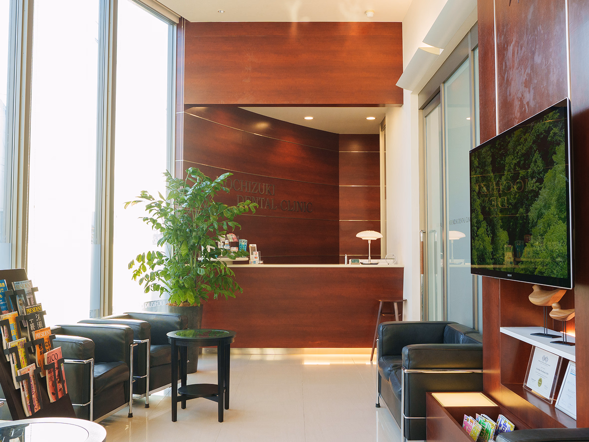 木目調の受付カウンターと待合スペースがある歯科クリニックのロビー