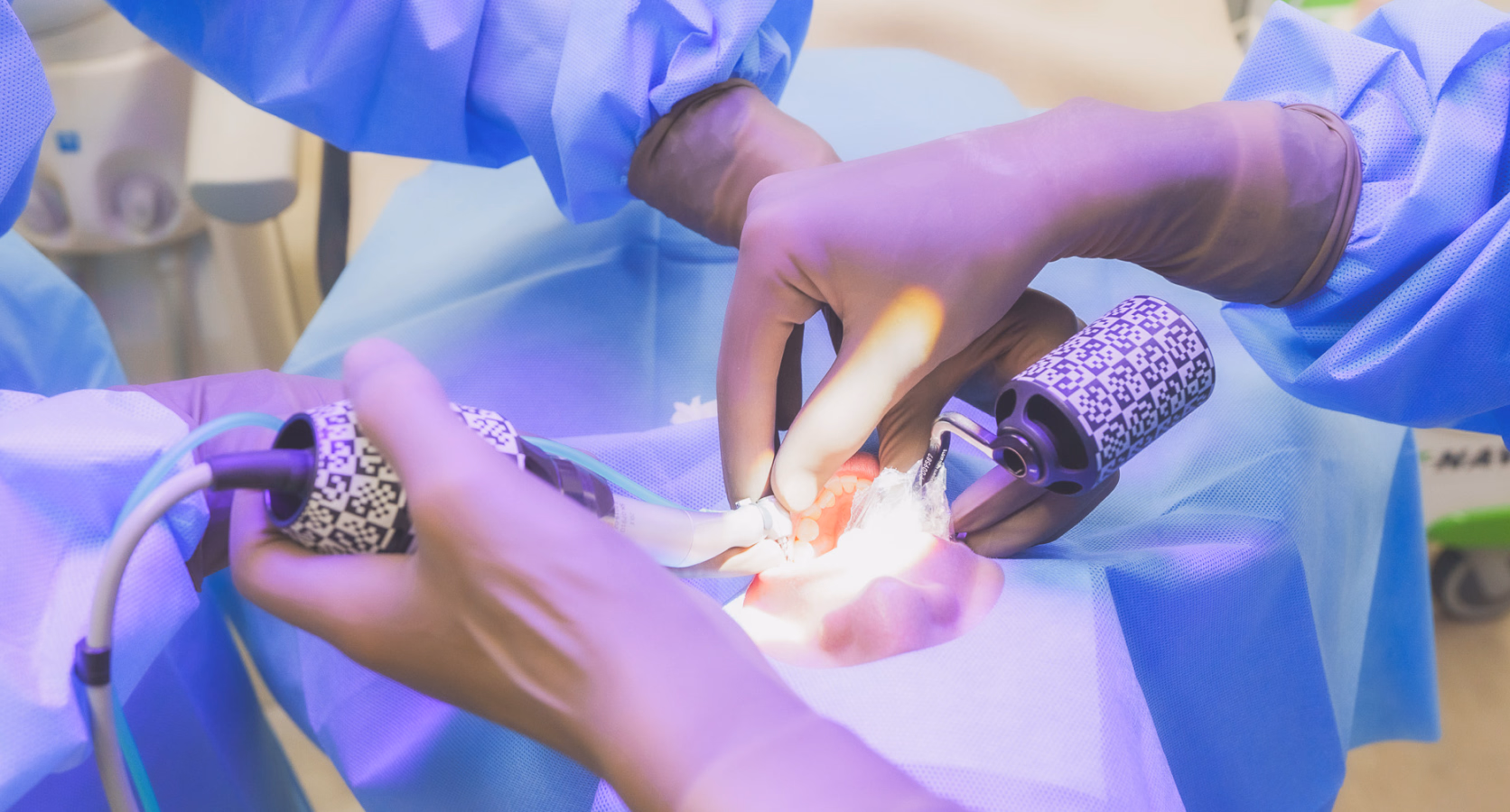 歯科治療の手術シーン。スタッフが手袋を着け、患者の口内をライトで照らしながら治療している。
